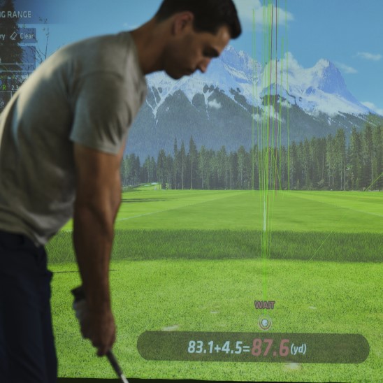 Uneekor screen in golf simulator with golfer ready to hit